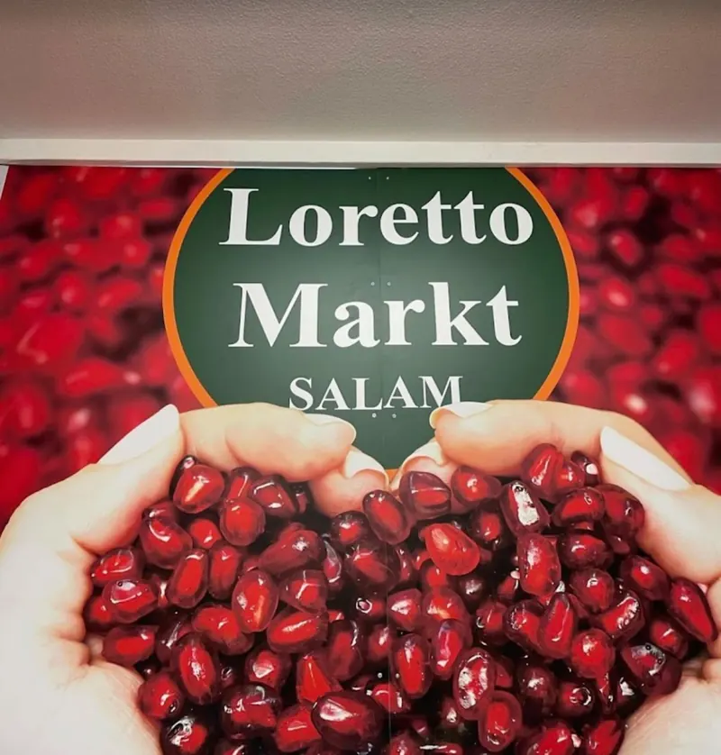 Wand im Loretto Markt: Granatapfelkerne und das Logo Loretto Markt Salam